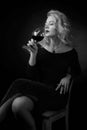 Attractive middle age woman in black evening dress with glass of red wine Royalty Free Stock Photo