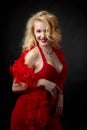 Attractive middle age woman in red evening dress with fluffy feather boa Royalty Free Stock Photo