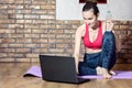 Attractive middle-aged brunette takes a break from exercises while sitting on a gym Mat, drinking water, and overcame instructiona