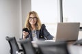 Attractive middle aged businesswoman using mobile phone and laptop at the office Royalty Free Stock Photo