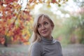 Attractive middle aged caucasian woman with green eyes at autumn park, smiling, alone. Casual wear. Precious age concept.