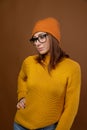 Attractive middle-aged Caucasian woman wearing a yellow sweater hat and glasses looks down to the side. Vision problem