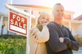 Attractive Middle-aged Couple In Front House and For Sale Real Estate Sign Royalty Free Stock Photo