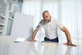 Attractive middle aged Caucasian entrepreneur, successful sales manager, businessman standing near flip chart with copy space for Royalty Free Stock Photo