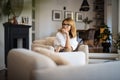 Attractive middle aged woman daydreaming in an armchair in a modern home Royalty Free Stock Photo