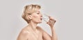 Attractive middle aged woman drinking fresh cold water from a glass while posing isolated over grey background Royalty Free Stock Photo