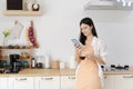 An attractive middle aged woman drinking her morning coffee and text messaging while relaxing at home in her kitchen Royalty Free Stock Photo