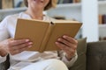 Attractive middle aged woman enjoying reading a book sitting on the sofa in her living room smiling while she reading Royalty Free Stock Photo