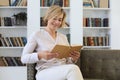 Attractive middle aged woman enjoying reading a book sitting on the sofa in her living room smiling while she reading Royalty Free Stock Photo