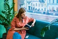 Attractive middle aged woman enjoying reading book, sitting on sofa in her Royalty Free Stock Photo