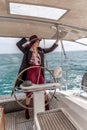 Attractive middle-aged woman at the helm of a yacht on a summer day. Luxury summer adventure, outdoor activities. Royalty Free Stock Photo