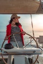 Attractive middle-aged woman at the helm of a yacht on a summer day. Luxury summer adventure, outdoor activities. Royalty Free Stock Photo