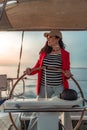 Attractive middle-aged woman at the helm of a yacht on a summer day. Luxury summer adventure, outdoor activities. Royalty Free Stock Photo