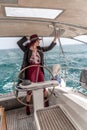 Attractive middle-aged woman at the helm of a yacht on a summer day. Luxury summer adventure, outdoor activities. Royalty Free Stock Photo