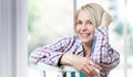 Attractive middle-aged woman looking relaxed at the camera, sitting near the window. The beautiful face close up Royalty Free Stock Photo