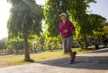 Attractive middle aged woman running happy at city park . beautiful and sporty lady on her 40s exercising doing jogging workout on Royalty Free Stock Photo