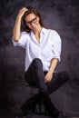 Studio portrait of a brunette haired attractive woman wearing white shirt and black jeans while posing at isolated dark background Royalty Free Stock Photo