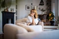 An attractive middle aged woman wearing casual clothes and relaxing in an armchair in her modern home Royalty Free Stock Photo