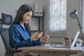 Attractive millennia Asian female holding her smartphone and credit card, using mobile banking app or online shopping Royalty Free Stock Photo