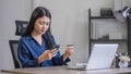 Attractive millennia Asian female holding her smartphone and credit card, using mobile banking app or online shopping Royalty Free Stock Photo