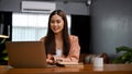 Attractive Asian businesswoman working in her private office, using laptop computer Royalty Free Stock Photo