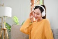Attractive Asian woman listening to music, relaxing on sofa in her living room Royalty Free Stock Photo