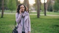 Attractive mixed race girl talking smartphone and drinking coffee in city park with bags. Young woman after shopping on Royalty Free Stock Photo