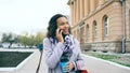 Attractive mixed race girl talking smartphone and drinking coffee walks in city street with bags. Young woman walking Royalty Free Stock Photo