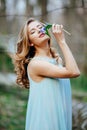 Attractive model in blue dress smell snowdrop flowers in the spring forest