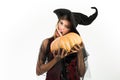 Attractive model girl in Halloween costume. Beauty Woman posing with Pumpkin and Halloween hat. Happy gothic young woman