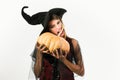 Attractive model girl in Halloween costume. Beauty Woman posing with Pumpkin and Halloween hat. Happy gothic young woman Royalty Free Stock Photo