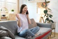 Attractive model sitting on cosy couch in bright living room having a phone call Royalty Free Stock Photo