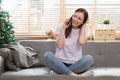 Attractive model sitting on cosy couch in bright living room having a phone call Royalty Free Stock Photo