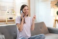 Attractive model sitting on cosy couch in bright living room having a phone call Royalty Free Stock Photo