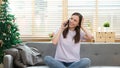 Attractive model sitting on cosy couch in bright living room having a phone call Royalty Free Stock Photo