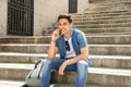 Handsome modern happy young man talking on his smart phone outside in the city. Royalty Free Stock Photo