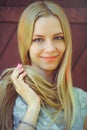 Attractive modest young blond woman playing with hair on red wooden background her hair painted in pink striped striped, in blue d Royalty Free Stock Photo