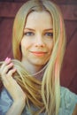 Attractive modest young blond woman playing with hair on red wooden background her hair painted in pink striped striped, in blue d Royalty Free Stock Photo