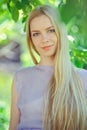 Attractive modest young girl with blond dren hair and natural make-up in purple dress outdoors, tenderness and softness on nature