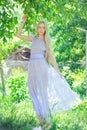 Attractive modest young girl with blond hair and natural make-up in purple dress outdoors, tenderness and softness on nature