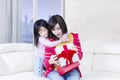 Attractive mother and girl open a gift on sofa Royalty Free Stock Photo