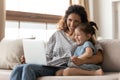 Mother and little daughter having fun watching cartoons on laptop