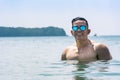 An attractive and muscular asian tourist in sunglasses enjoys the beach, partially immersed in chest deep waters. Summertime Royalty Free Stock Photo