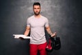 Attractive muscular caucasian man holding sports items and books, promoting a healthy lifestyle