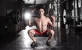 Attractive muscular crossfit athlete doing squat exercise in mo