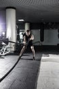 Attractive muscular man working out with heavy ropes. Photo of handsome man in sportswear. Crossfit