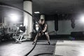 Attractive muscular man working out with heavy ropes. Photo of handsome man in sportswear. Crossfit