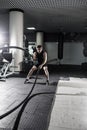 Attractive muscular man working out with heavy ropes. Photo of handsome man in sportswear. Crossfit