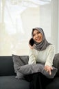 Attractive Muslim woman enjoys talking on the phone with her friend while relaxing in living room Royalty Free Stock Photo