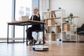 Woman turning on robotic vacuum via remote control at work